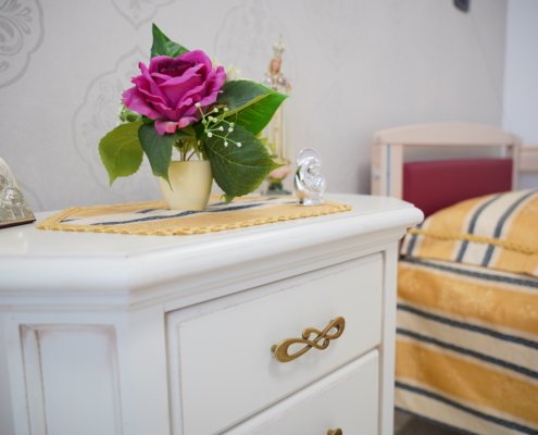 dettaglio maniglia dorata intarsiata comodino con fiori e lettino ortopedico regolabile